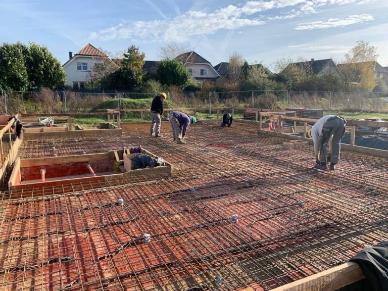 Arbeiter verlegen Bewehrungsmatten auf einer Bodenplatte vor der Betonage