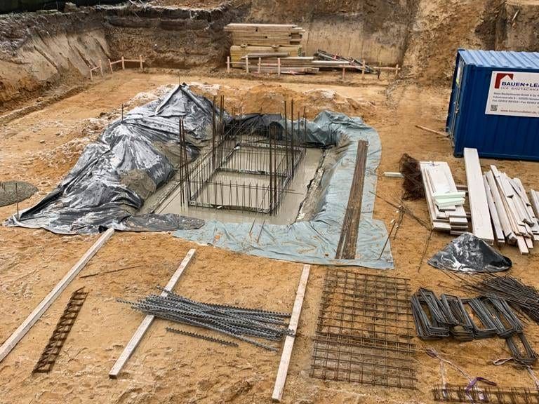 Ausgehobene Fundamentgräben mit eingelegten Bewehrungskörben und Abdeckfolie